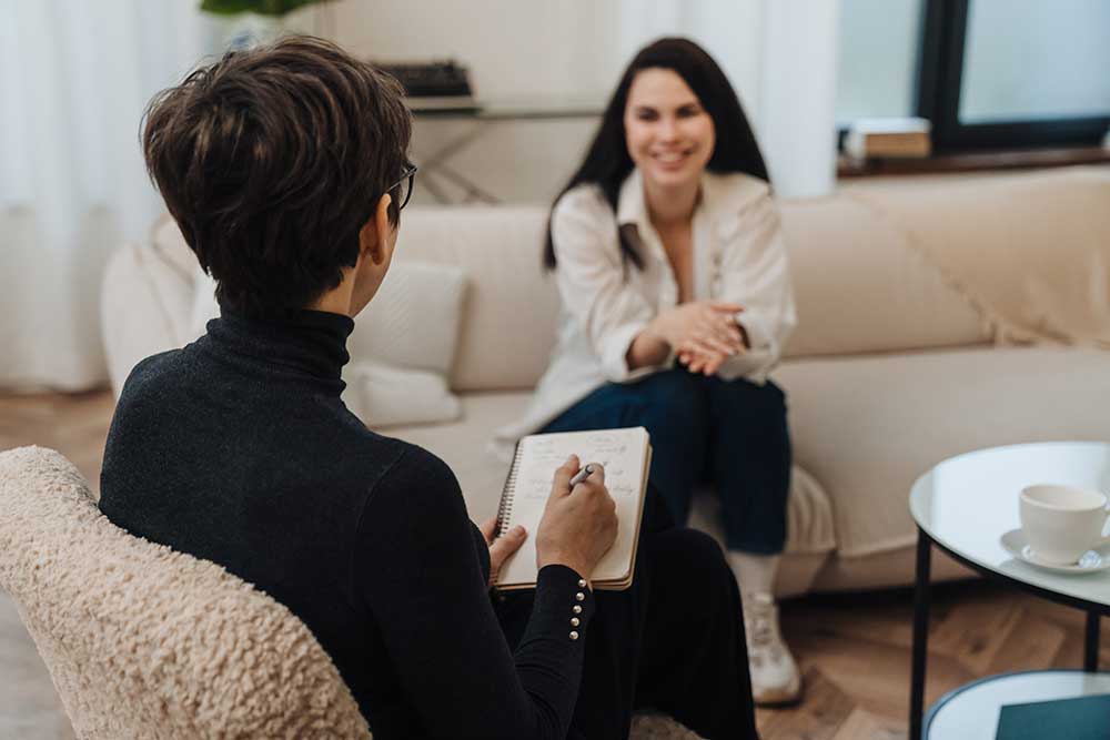 Writing down notes during therapy session with smiling woman