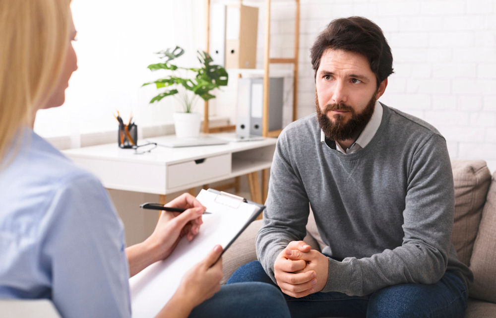 Man listens to therapist during evaluation for addiction treatment